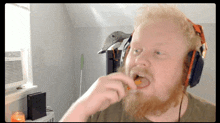 a man with a beard is wearing headphones and eating a piece of food