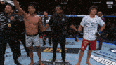 a man in a white shirt with the word ufc on it stands in a boxing ring