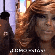 a woman with long hair is standing in front of a man and a sign that says `` como estas '' .