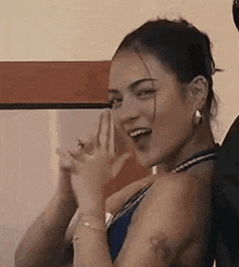 a woman in a blue bikini is laughing and clapping her hands while standing next to a man .