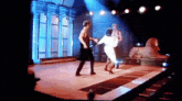 a man and woman are dancing on a stage with a sign that says hollywood