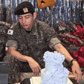 a man in a military uniform is sitting next to a cake .