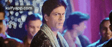 a man is standing in front of a crowd of people and making a funny face .