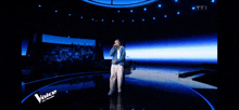 a man singing into a microphone on a stage with the word voice in the corner
