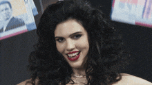 a woman with curly hair is smiling in front of a tv screen that says 100