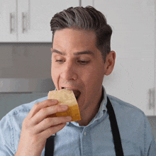 a man wearing an apron is eating a piece of bread