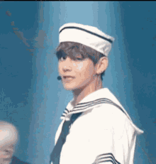 a young man in a sailor suit and hat is standing on a stage .