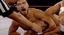 a referee is holding a wrestler 's head in a wrestling match .