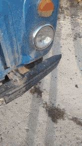 a close up of a blue car 's headlight on a gravel road