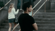 a man in a black shirt is standing on stairs with his arms crossed