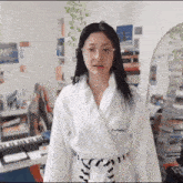 a woman is wearing a white robe with mac embroidered on it