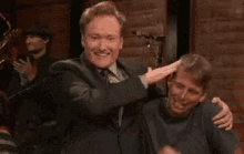 a man in a suit and tie is laughing with another man .