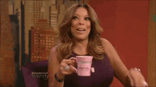 a woman is holding a pink wendy mug