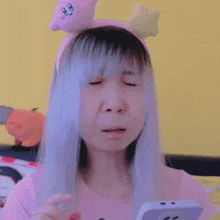 a woman wearing a pink kirby headband is looking at her phone