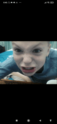 a young boy laying on a bed making a funny face