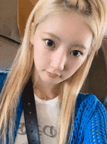 a young woman with blonde hair is wearing a blue cardigan and a white shirt