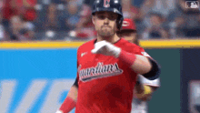 a baseball player is wearing a red uniform and giving a thumbs up during a game .