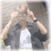 a man wearing sunglasses is standing in front of a brick wall with kaiwen de yumi 3 written below him