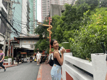a woman in a black tank top stands in front of a street with a sign that says ' chinese ' on it