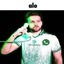 a man with a beard is talking on a phone while wearing a shirt that says whatsapp .