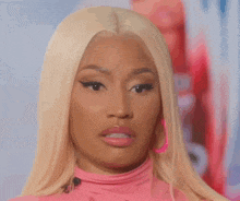 a close up of a woman with blonde hair wearing a pink shirt