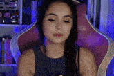 a woman is sitting in a pink gaming chair and looking at the camera .