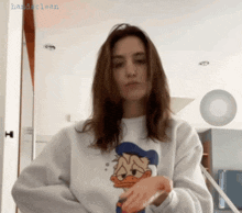 a woman wearing a donald duck sweatshirt wipes her hands