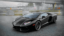 a black lamborghini is parked in a parking lot under a bridge