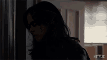 a woman is standing in a dark room with a netflix logo on the bottom right