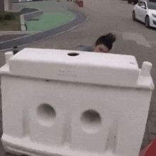 a woman is standing behind a white barrier on a street .