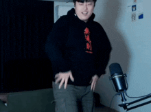 a man in a black hoodie is dancing in front of a microphone .