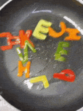 a frying pan filled with colorful peppers that spell out the letters e u h i j k e