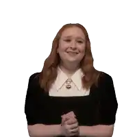 a woman with red hair wearing a black shirt and white collar is smiling