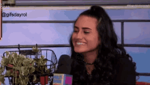a woman is smiling in front of a sign that says gifsdayrol on it