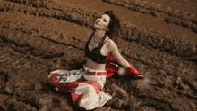 a woman laying in the mud with a necklace that says louis vuitton on it