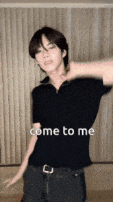 a young man in a black shirt is dancing in front of a window with the words come to me on the bottom .
