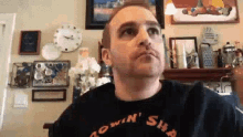 a man wearing a black shirt is sitting in a living room .