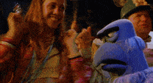 a woman in a pink jacket stands next to a blue bird