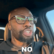 a man with glasses and a beard says no in a car
