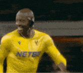 a soccer player wearing a yellow jersey that says netbet