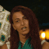 a woman with red hair and a green scarf around her neck is making a funny face .