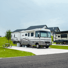 a silver rv parked in a grassy area with a picnic table in front of it