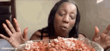 a woman is eating a casserole dish of food with her hands .
