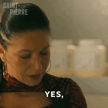 a woman is smiling and saying yes in front of a shelf of bottles .