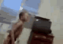a blurry picture of a man standing next to a suitcase in a room .