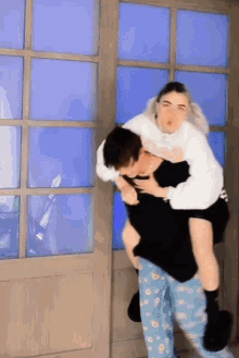 a man is carrying a woman on his back in front of a blue door .
