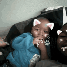 a man is holding a baby with cat ears and a t on his face