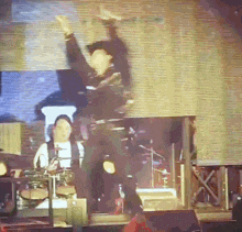 a man is dancing on a stage in front of a large screen