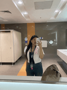 a woman taking a selfie in a public bathroom