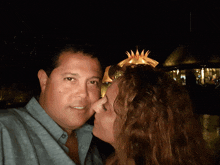 a woman kisses a man on the cheek in front of a thatched hut at night